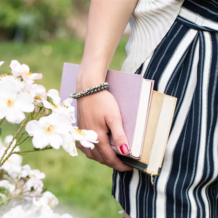 Frau mit Büchern in Rosengarten